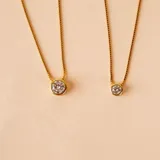 Conjunto de tres collares de cadena fina en plata 925 con baño de oro, cada uno con un dije de punto de luz en forma de circonia engastada.