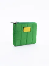 Monedero acolchado color naranja, de diseño rectangular con cierre superior y detalle de parche rectangular azul en el frente.