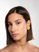 Aros tipo botón con diseño de flor amarilla y centro decorado con pequeñas cuentas doradas.