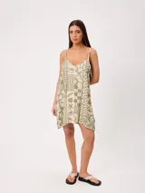 Vestido corto de algodón estampado, color verde, con tirantes finos y escote en V. Presenta un diseño holgado con estampado de patrones mixtos que incluyen motivos tropicales y geométricos.