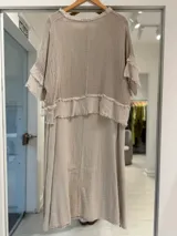 Vestido midi beige de corte holgado, compuesto por una capa superior de tejido de red transparente con mangas cortas y detalles deshilachados, sobre una base de tela lisa.