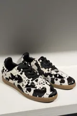 Championes de cuero vacuno con acabado brillante tipo charol, color azul marino, con cordones al tono y suela de goma color caramelo.