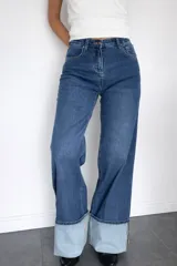 Pantalón de jean corte wide leg en color azul oscuro, con tiro medio-alto y detalle de dobladillo ancho en la botamanga que contrasta con el tono del resto de la prenda.