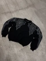 Sweater negro con cuello redondo y diseño geométrico en gris en la parte superior del pecho y hombros.