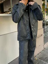 Campera de cuero sintético color gris oscuro, con cuello camisero, cierre frontal con cremallera dorada y bolsillos laterales.