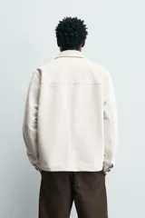 Sobrecamisa regular fit color verde oscuro, confeccionada en tejido efecto ante. Cuenta con cuello solapa, manga larga con puño abotonado, bolsillos de plastrón con solapa en el pecho y bolsillos de vivo en la cadera. El cierre es frontal con botonadura.