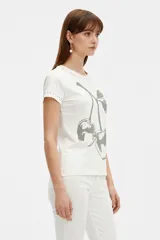 Remera negra de manga corta, con cuello redondo y ajuste al cuerpo. Cuenta con un gran estampado floral en tono gris en el frente y detalle de tachas plateadas alrededor del cuello y en los puños.