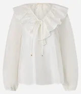 Blusa color blanco confeccionada en voile, de mangas largas con elástico en los puños, cuello en V con volado y lazo con adornos metalizados.