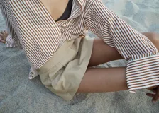 Camisa de corte recto y diseño a rayas verticales en tonos terracota y blanco, con cuello camisero, cierre frontal de botones y mangas largas con puños abotonados.