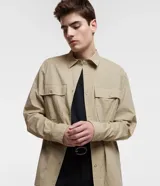 Camisa overshirt color beige, de corte recto, con cuello solapa, abotonadura frontal, mangas largas y dos bolsillos de parche con solapa en el pecho.