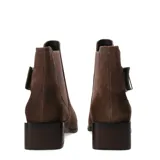 Botas tipo chelsea de cuero negro con acabado texturizado, taco cuadrado bajo y detalle de tira lateral con hebilla metálica.