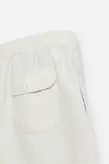 Bermuda relaxed fit confeccionada en tejido ligero de cáñamo. Presenta cintura elástica ajustable con cordón interior, bolsillos laterales y un bolsillo trasero de plastrón con solapa.
