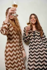 Vestido largo de lurex con diseño de patrón en zigzag en tonos tostado y marrón, escote en V con cordones para atar y mangas largas.