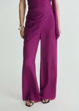 Pantalon de vestir de corte recto y tiro medio, confeccionado en viscosa de color fucsia. Presenta una cintura elástica y un diseño fluido con una sobrecapa lateral que aporta movimiento.