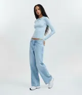Blusa de punto de manga larga con cuello polo y cierre frontal parcial. Presenta un diseño ajustado al cuerpo en color blanco con detalles de ribetes en contraste en el cuello, puños y ruedo.