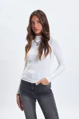 Remera de manga larga con cuello alto, confeccionada en tela lisa de color blanco, con ajuste al cuerpo.