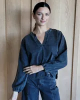 Blusa azul con cuello en V y mangas largas abullonadas con puños elásticos.