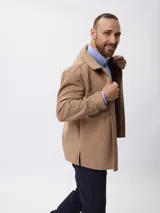 Sobrecamisa de paño color beige, con cuello clásico, cierre frontal con botones metálicos y bolsillos frontales. Presenta un diseño de corte recto y aberturas laterales en el ruedo.