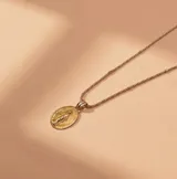 Conjunto compuesto por una cadena de eslabones y un dije ovalado de la Virgen Milagrosa, elaborado en plata y oro.
