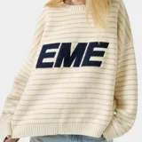Sweater de punto color crema con finas rayas horizontales en beige. Presenta un logo grande con la palabra "EME" en azul marino en el frente y tiene cuello redondo y corte holgado.