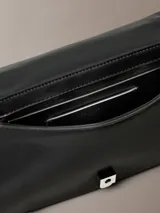 Cartera acolchada Calvin Klein de mano, color negro, con diseño matelassé en rombos, asa superior y correa de cadena metálica. Incluye pequeño logo metálico en la parte frontal.