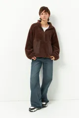 Buzo negro de teddy con cuello alto y cierre de cremallera parcial. Presenta bolsillos de nylon en la parte inferior delantera.