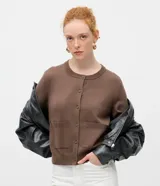 Cardigan de punto color beige, de corte clásico y manga larga, con cuello redondo, cierre frontal por botones y bolsillos delanteros funcionales.