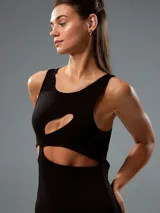 Minivestido negro ajustado al cuerpo, sin mangas y con aberturas asimétricas en el frente.