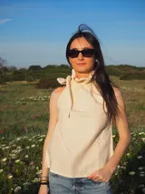 Blusa de lino sin mangas, con cuello alto fruncido y un lazo decorativo al costado. Diseño a rayas finas en tonos amarillo manteca y blanco, con corte recto y ligero.