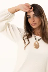 Blusa de cuello redondo con mangas largas tipo globo y puños elásticos. Presenta un diseño de textura combinada en el frente y las mangas.