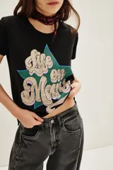 Remera de algodón color negro con estampa frontal gráfica que incluye una estrella verde y la frase Life on Mars en tipografía retro.