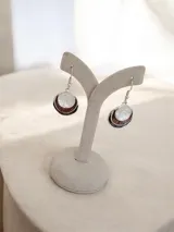 Aros colgantes tipo caravanas con diseño circular de tres capas en tonos blanco, tierra y oscuro, con gancho de plata.