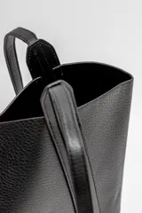 Bolso tipo tote de diseño minimalista, confeccionado en material texturizado color beige, con doble asa larga para llevar al hombro y costuras reforzadas en los laterales.