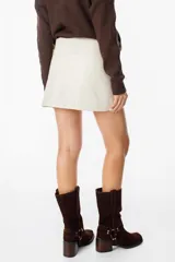 Mini falda tipo cruzada confeccionada en cuero, con detalle de cintura con tachas metálicas.