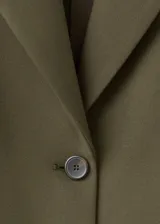 Blazer verde militar, de corte estructurado, con solapas de muesca, bolsillos con solapa y cierre frontal de un botón.