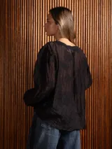 Blusa de tela liviana color bordó, con escote en V y detalles de bordado floral tono sobre tono. Presenta mangas largas con leve volumen y puños abotonados.