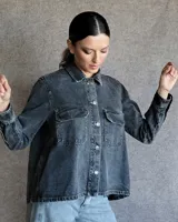 Sobrecamisa de denim azul con cuello camisero, cierre frontal con botones, mangas largas con puños abotonados y dos bolsillos con solapa en el pecho.