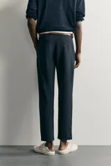 Pantalón chino negro slim fit de corte recto, con bolsillos frontales, trabillas para cinturón y cierre frontal con cremallera y botón.