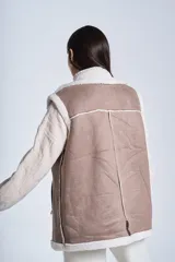 Chaleco símil cuero color marrón, con interior de corderoy color crema, cuello solapa y cierre frontal con cremallera.