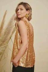 Musculosa de lentejuelas doradas con doble escote en V, tanto en el frente como en la espalda. Presenta breteles anchos y un corte levemente acampanado.