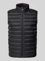 Chaleco acolchado negro Tommy Hilfiger, con cuello alto, cierre de cremallera, bolsillos laterales y logo bordado en el pecho.