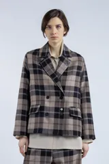 Blazer marrón con estampado a cuadros negros y blancos, de corte recto, solapa clásica, cierre cruzado con botones y bolsillos frontales.