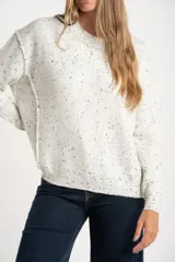 Sweater de punto con diseño jaspeado, cuello redondo y corte oversize. Presenta costuras visibles en los hombros y puños acanalados.
