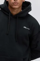 Buzo con capucha y bolsillo tipo canguro, de color crema, con pequeño estampado en el pecho y cordones ajustables en el cuello.