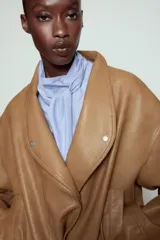 Chaqueta bomber ZW Collection confeccionada en tejido efecto piel de color marrón. Cuenta con cuello subido, manga larga con puño y botón a presión, bolsillos delanteros y bajo recto elástico. Cierre frontal cruzado con botones a presión.