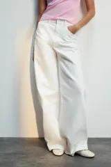 Jeans de mezclilla en color negro gastado, tiro alto, diseño de cinco bolsillos y corte de pierna ancha extra larga. Cuenta con cierre frontal de cremallera y botón metálico.