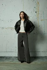 Jean de corte wide leg en color gris lavado, con diseño de aberturas laterales decoradas con tachas metálicas a lo largo de toda la pierna.