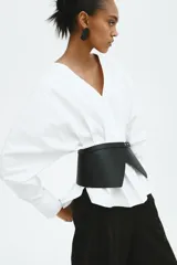 Blusa de algodón H&M Edition blanca con maxiescote en V, botones ocultos y canesú en la espalda. Presenta hombros caídos, mangas largas con puños abotonados y pinzas pronunciadas en la cintura que definen una silueta estructurada, con bajo asimétrico más largo en la espalda.