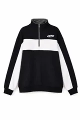 Buzo de cuello alto con cierre frontal parcial, diseño bicolor en negro y blanco, con mangas largas y puños elásticos.