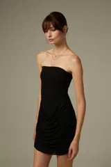 Vestido corto negro con apliques de strass, diseño ajustado al cuerpo, escote strapless y detalle drapeado en la parte frontal.